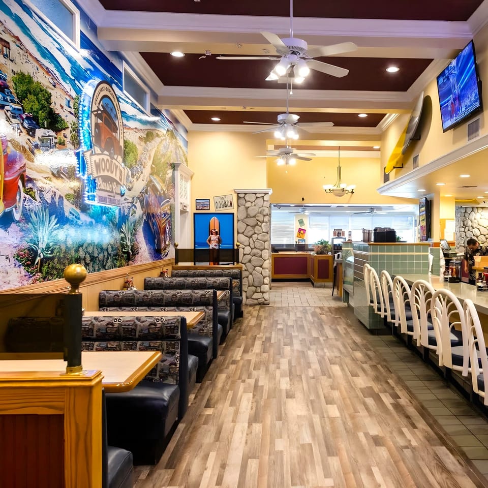Interior of Woody's Classic Grill with booths, counter seating, and a large mural on the left wall.