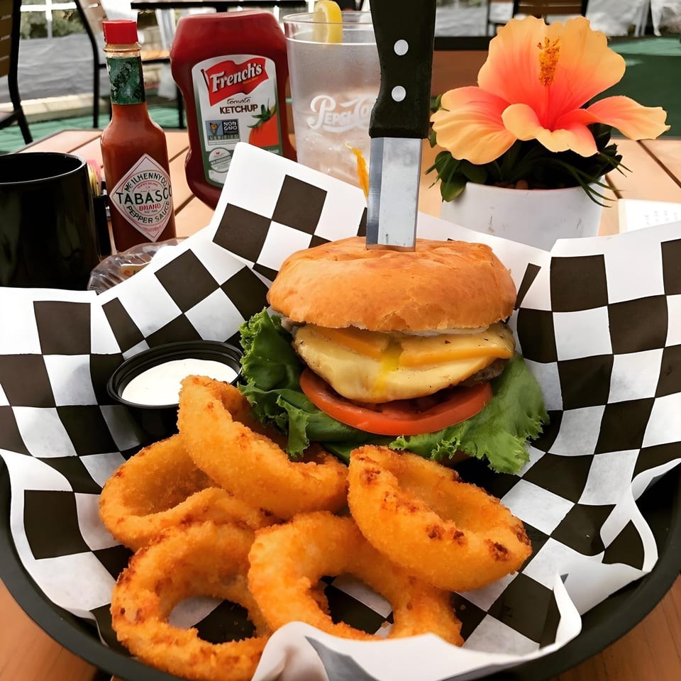 A Woody's Classic Grill burger with melted cheese, lettuce, tomato, and onion rings.